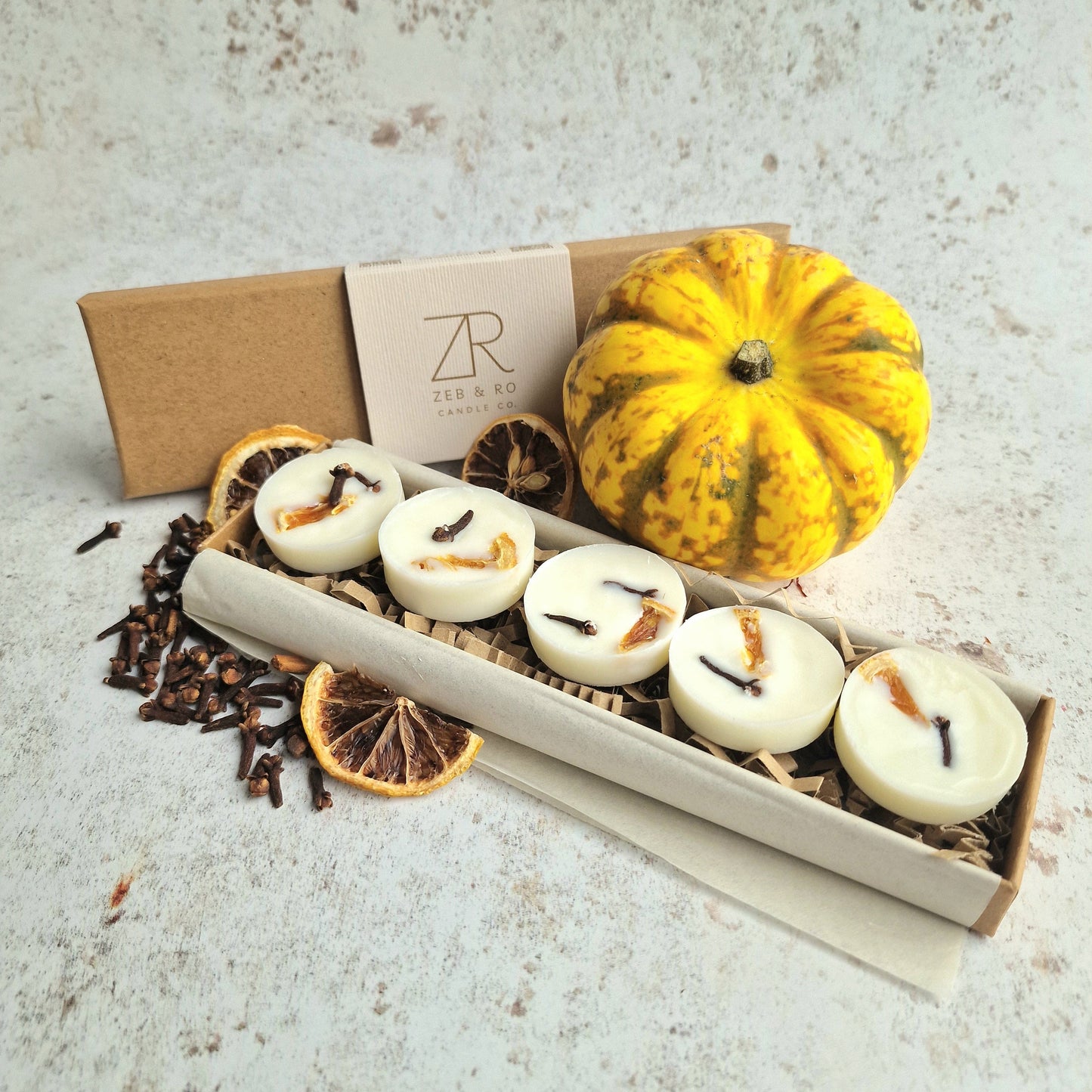 Box of candles with a small pumpkin and decorative items on a textured surface